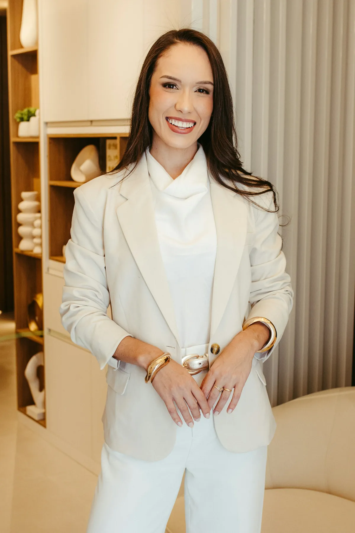 Esteticista responsável do Studio Lumi, sorrindo, de blazer claro
