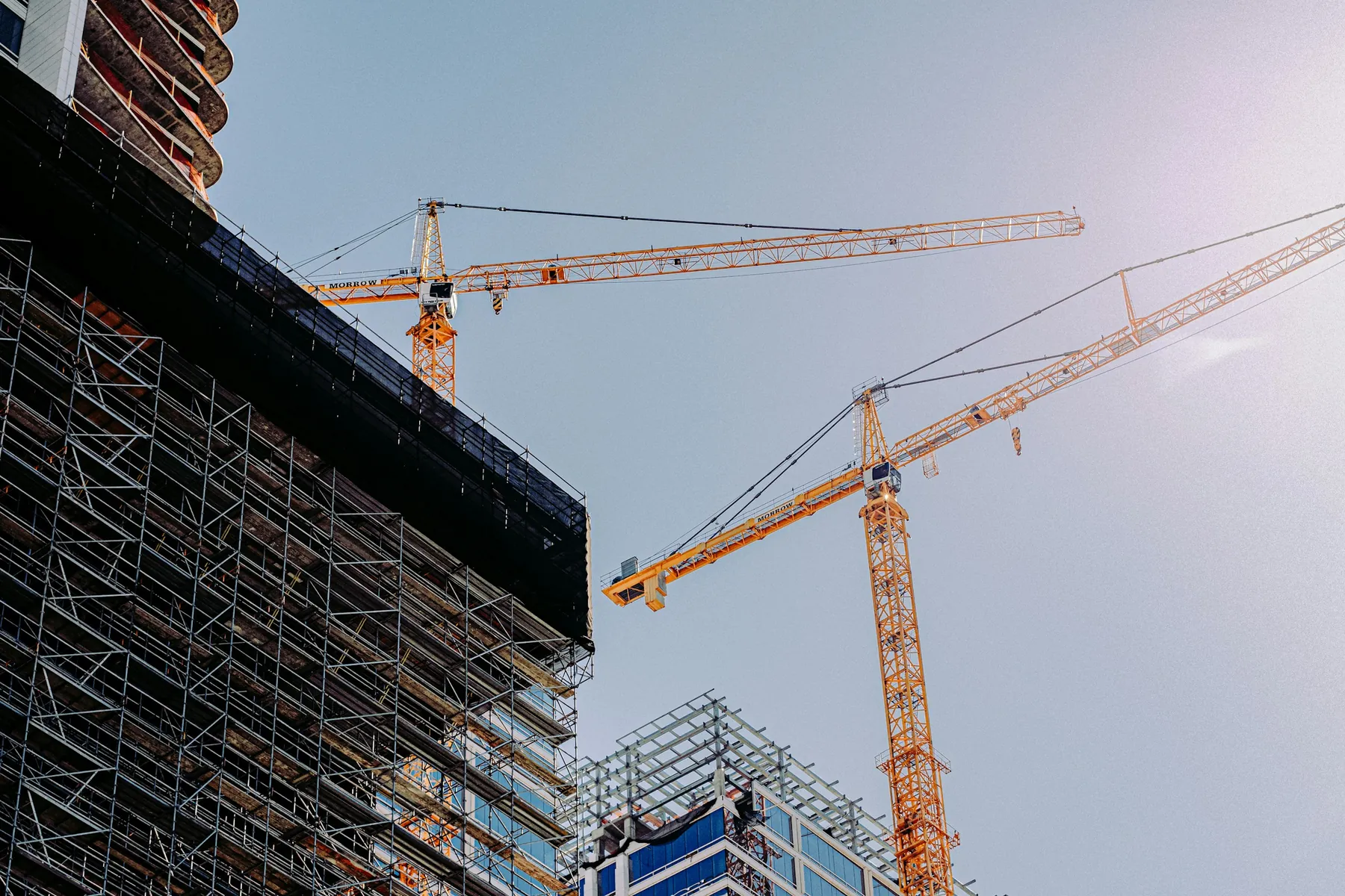 Guindastes sobre edifício em construção ao entardecer