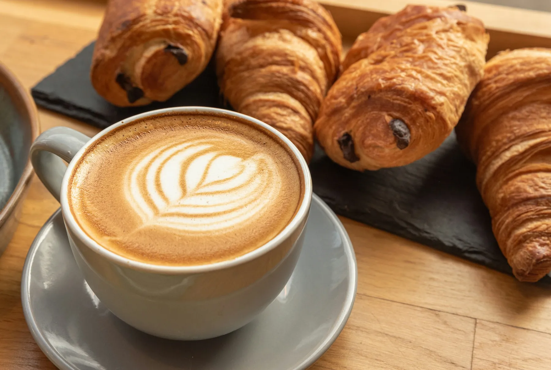 Café com latte art e croissants na mesa
